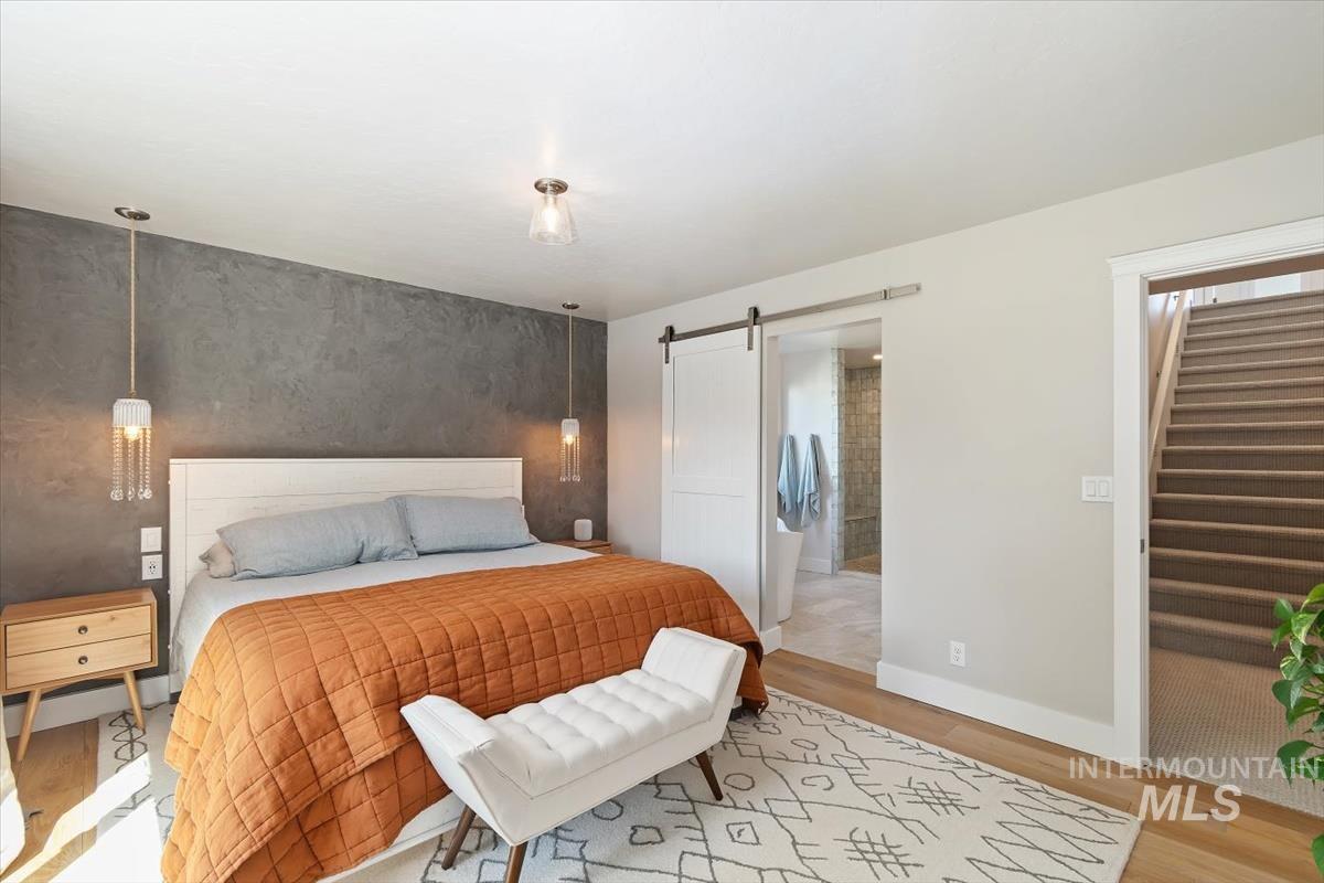 Bedroom with light wood finished floors, a barn door, and a spacious closet