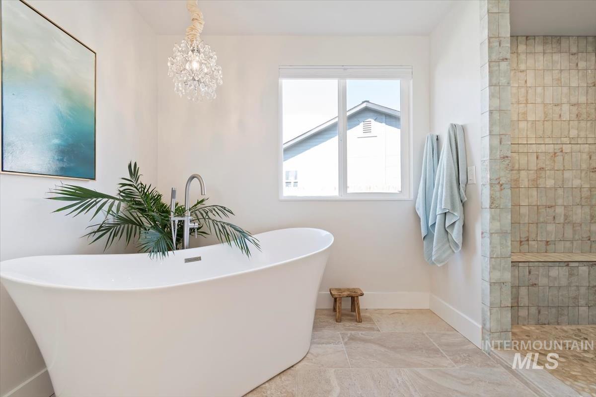 Bathroom with a soaking tub, a chandelier, and a walk in shower