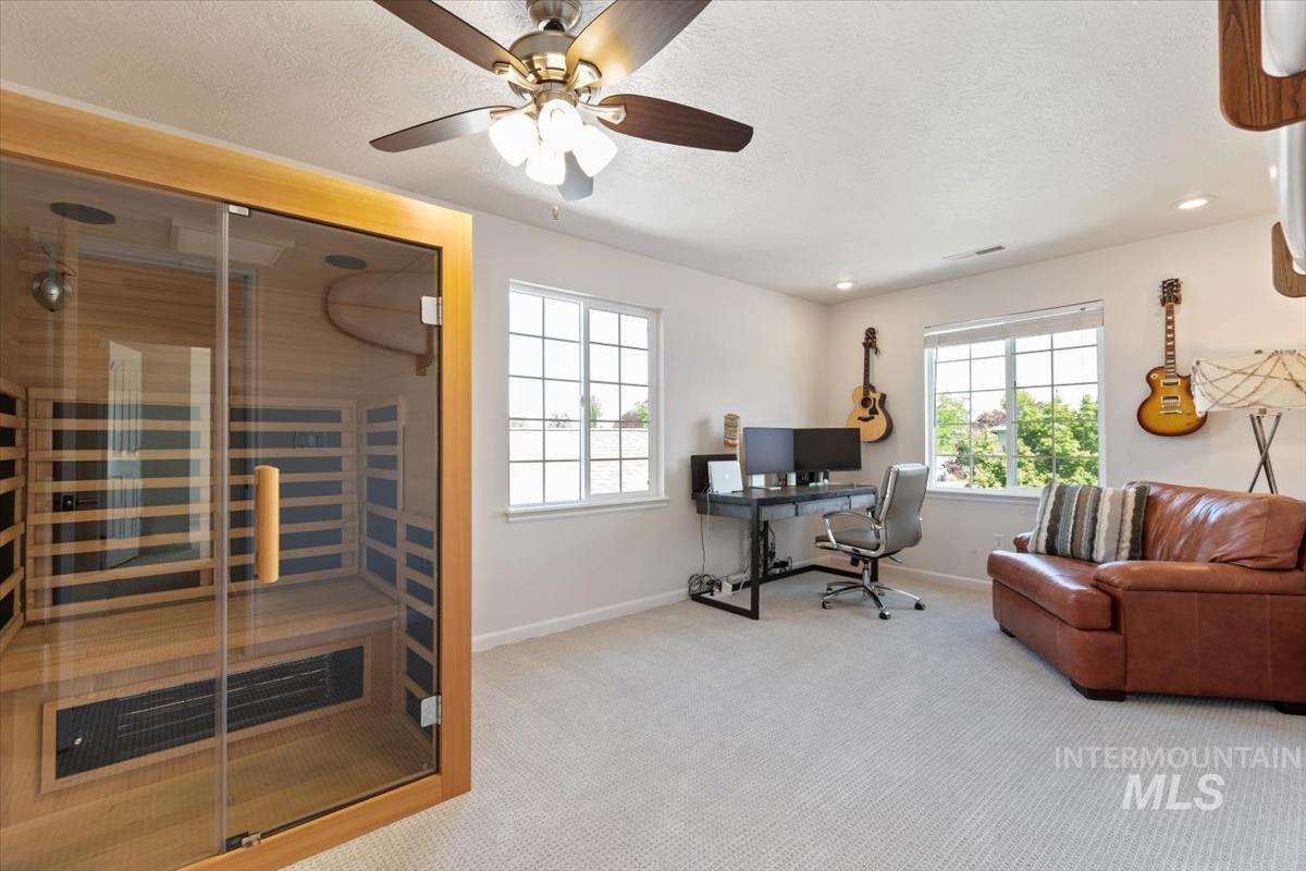 Home office featuring a relaxing sauna (negotiable), a textured ceiling, carpet floors, and a ceiling fan