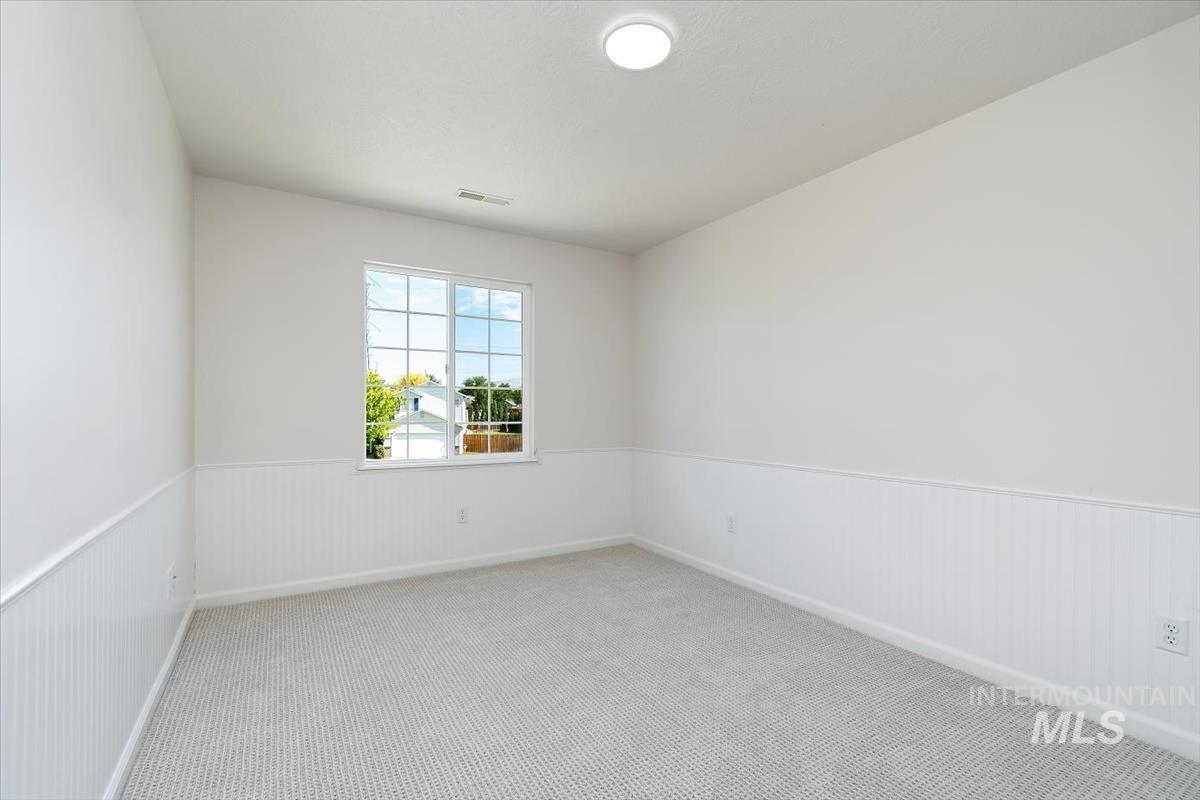 Unfurnished room with a wainscoted wall and carpet floors