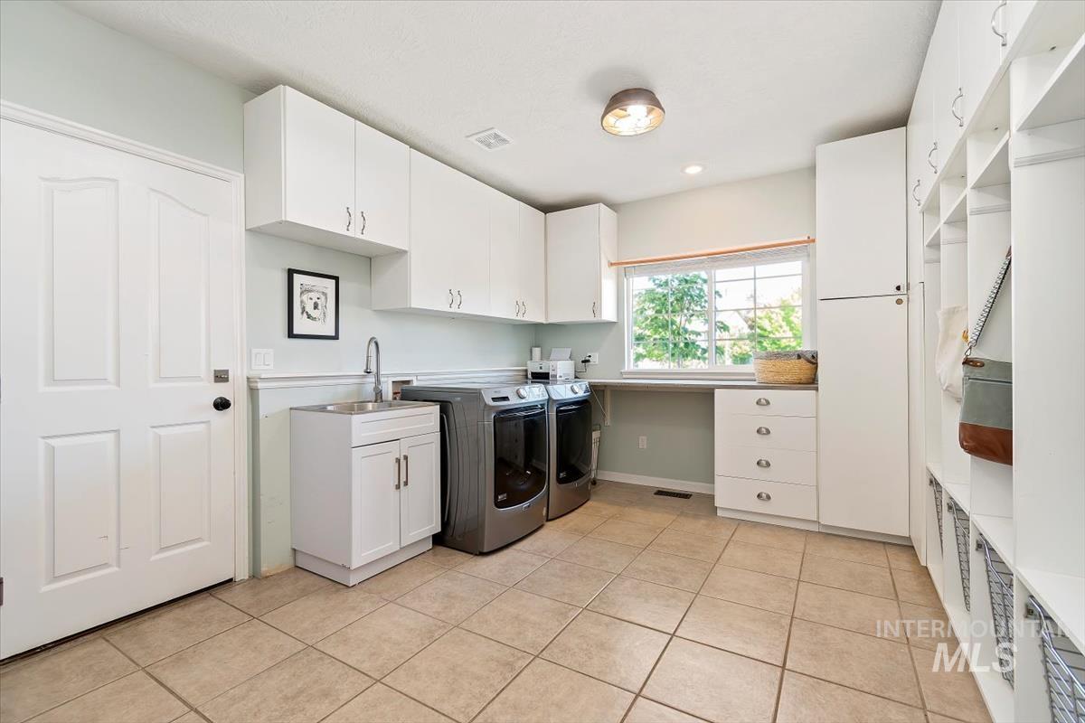 Laundry room featuring cabinet space, washer and dryer, and light tile patterned flooring