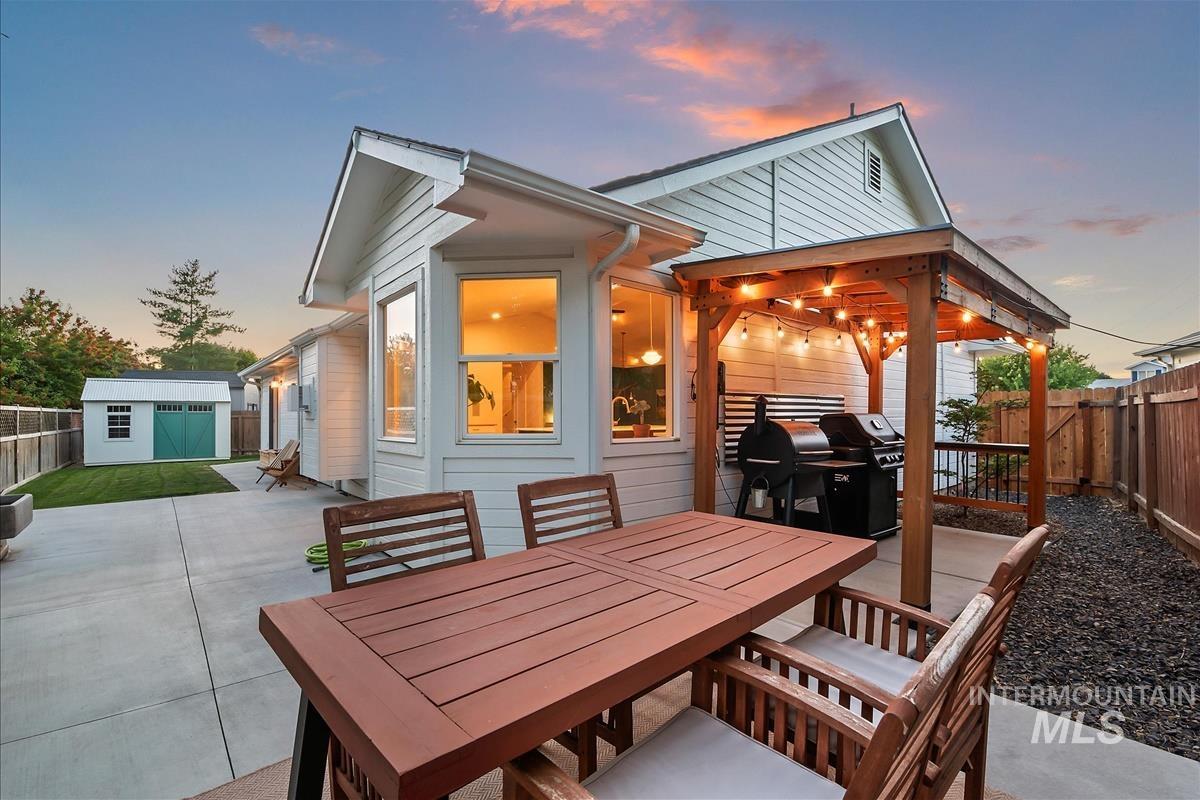 Patio terrace at dusk with a patio area, a fenced backyard, and outdoor dining space