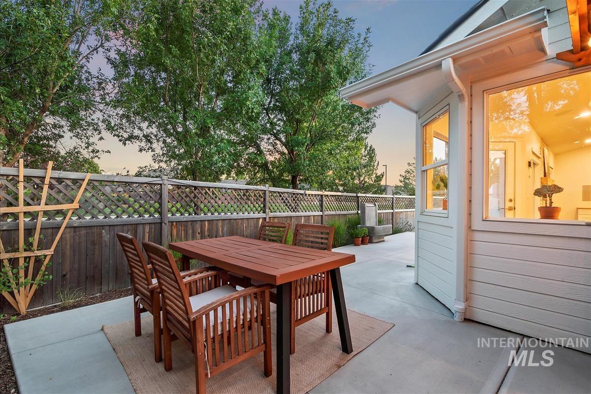 Patio terrace at dusk with a patio area, outdoor dining space, and a fenced backyard