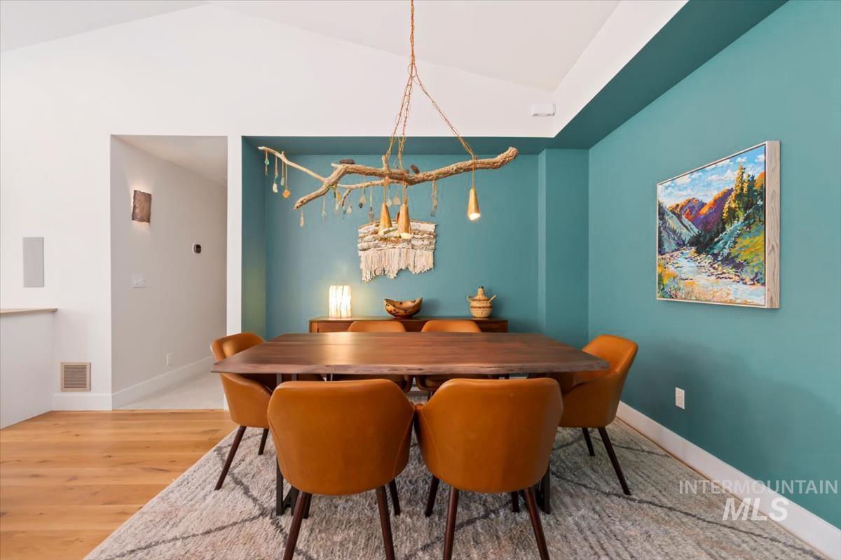 Dining area featuring light wood-type flooring, vaulted ceiling, and a chandelier