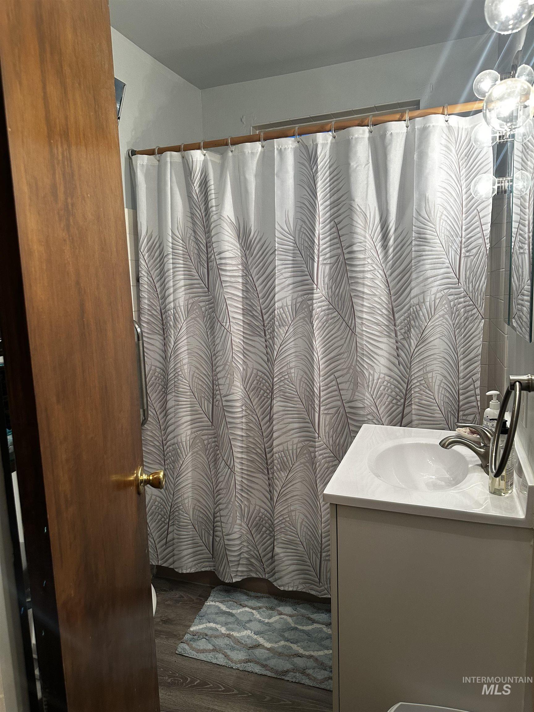 Full bath with vanity, dark wood finished floors, and curtained shower
