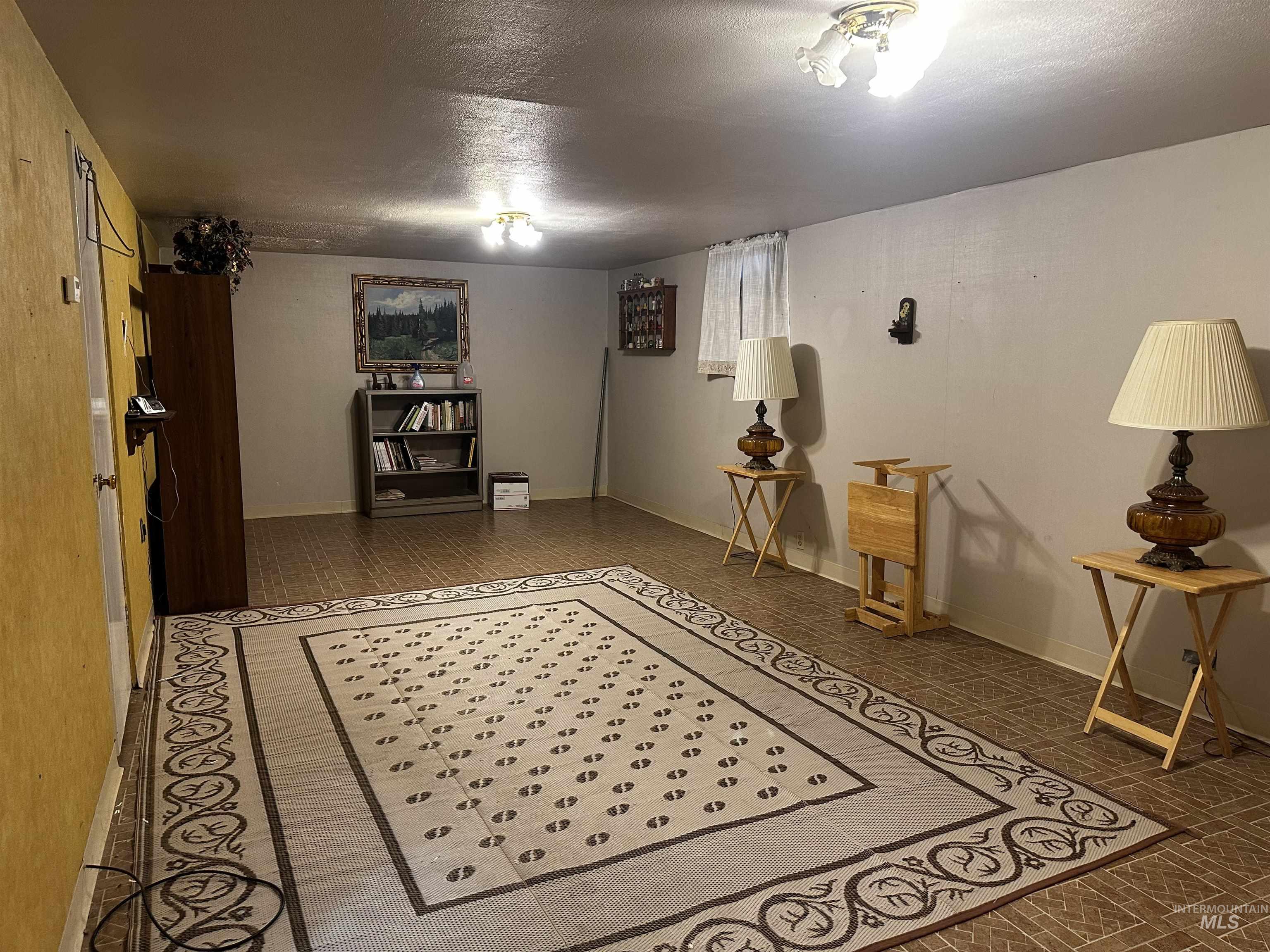 Basement with a textured ceiling and baseboards