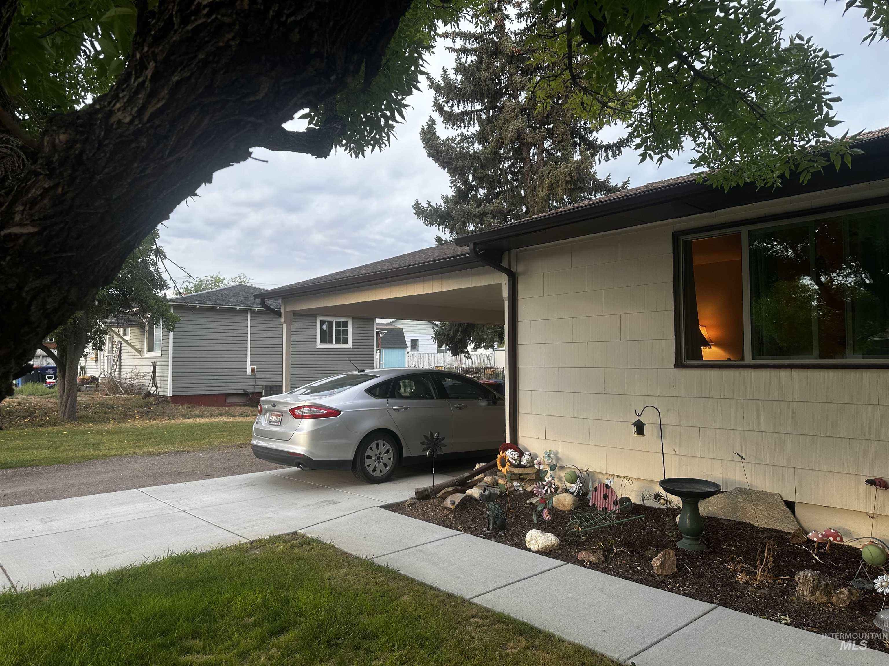 View of home's exterior with driveway, an attached carport, and a lawn