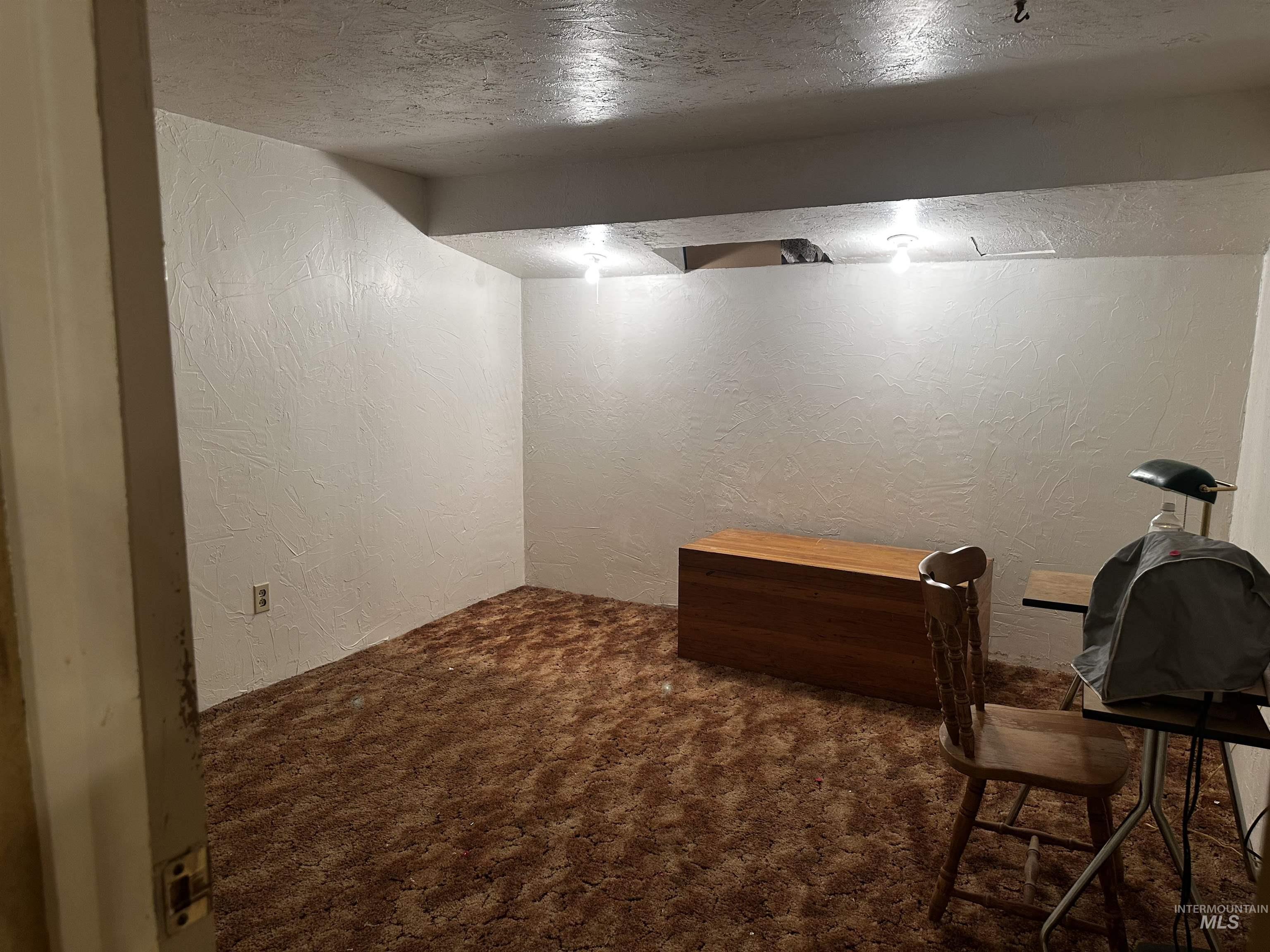 Office area featuring a textured wall and dark colored carpet