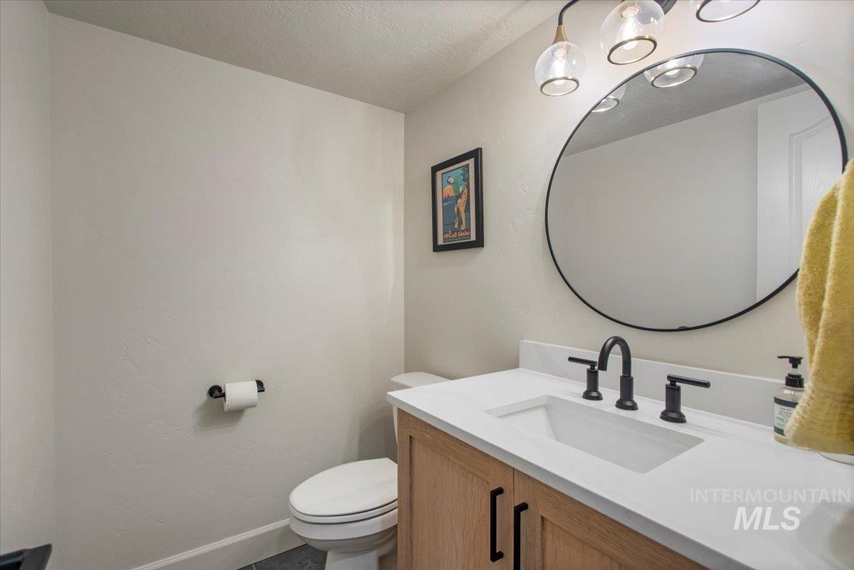 Half bath featuring a textured ceiling, vanity, and a textured wall