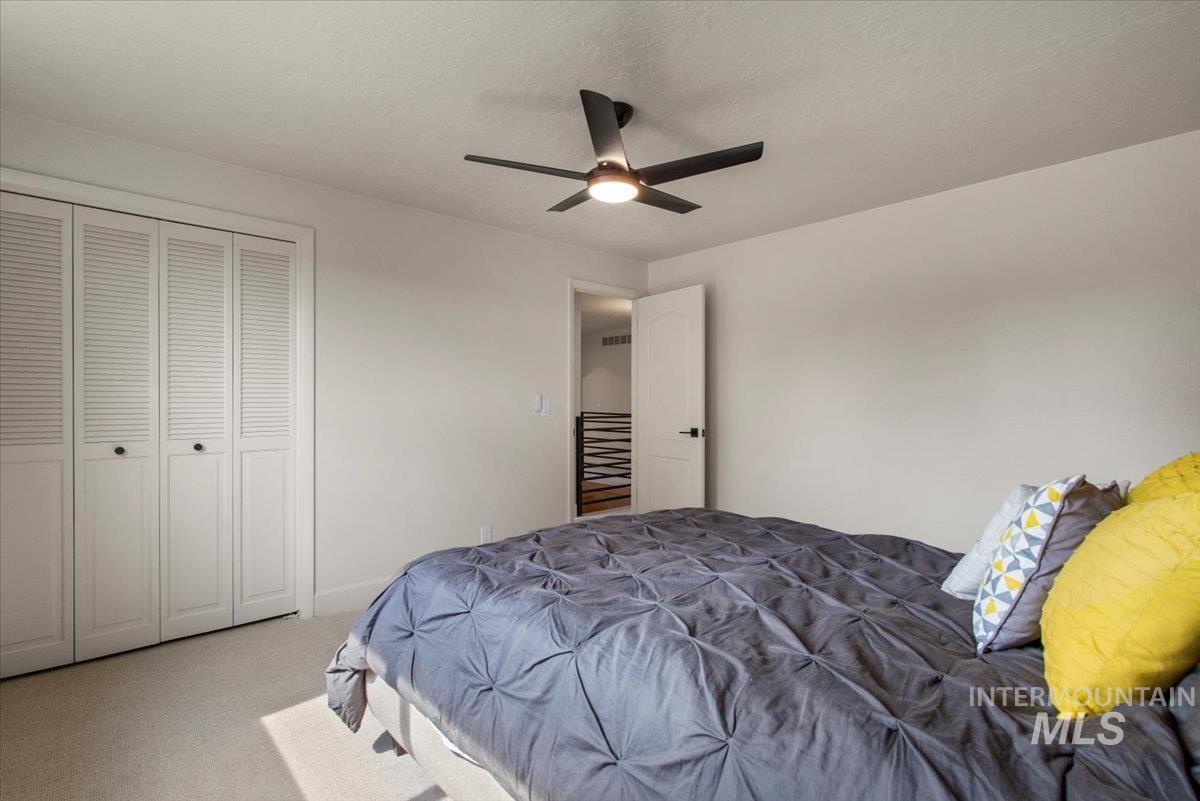 Carpeted bedroom with a closet, a ceiling fan, and a textured ceiling