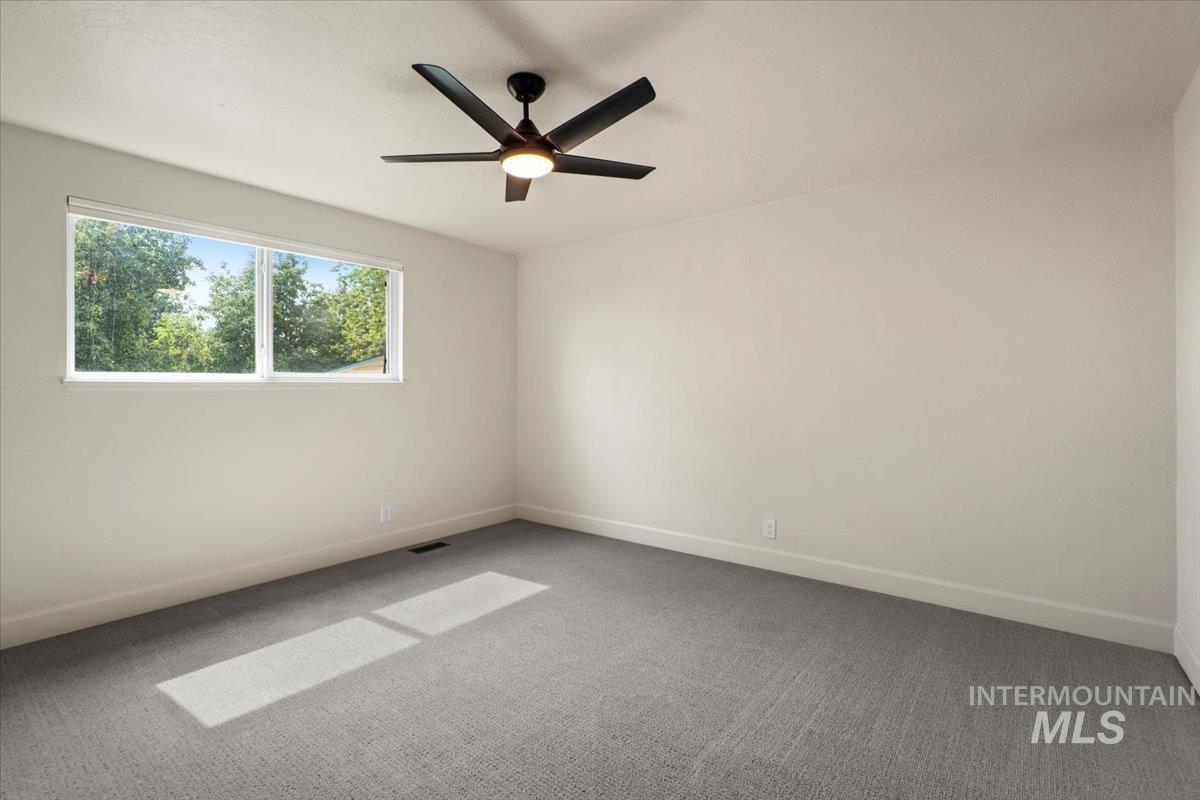 Empty room with carpet flooring and ceiling fan