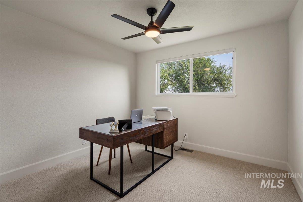 Office with light colored carpet and a ceiling fan