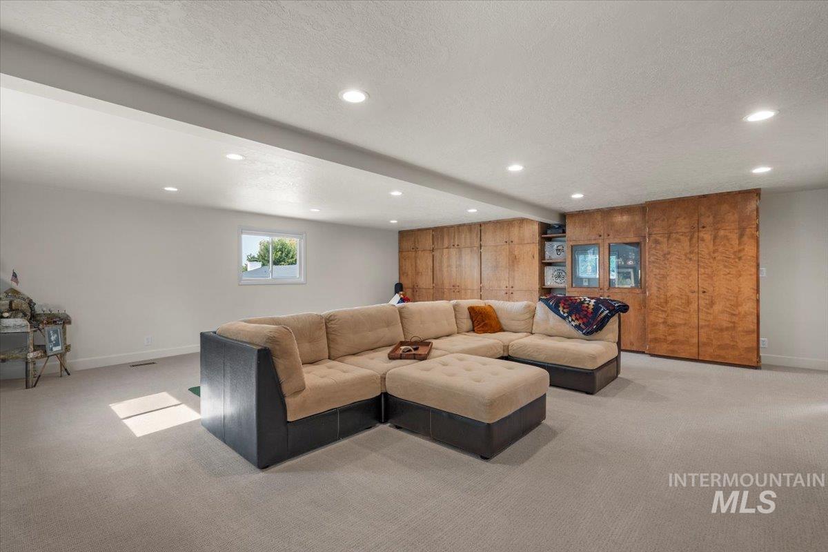 Living room with beamed ceiling, light carpet, a textured ceiling, recessed lighting, and wooden walls