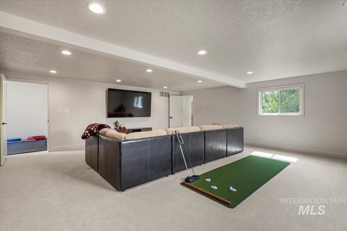 Living room featuring beam ceiling, light colored carpet, a textured ceiling, and recessed lighting