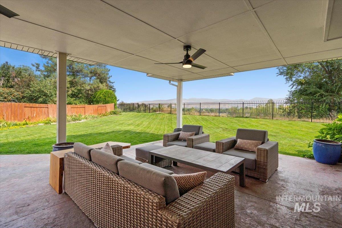 Fenced backyard with a patio area, outdoor lounge area, and a ceiling fan