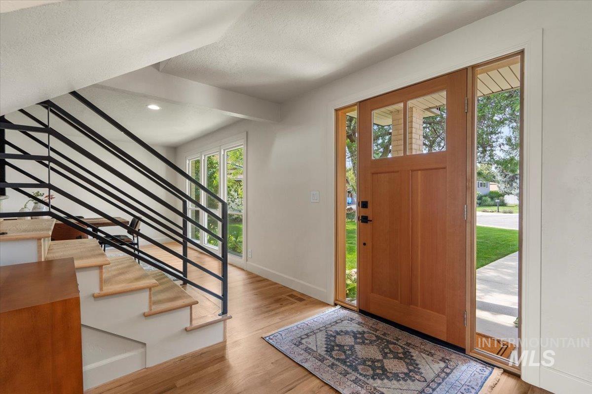 Foyer entrance with light wood-style flooring, a textured ceiling, stairway, and recessed lighting