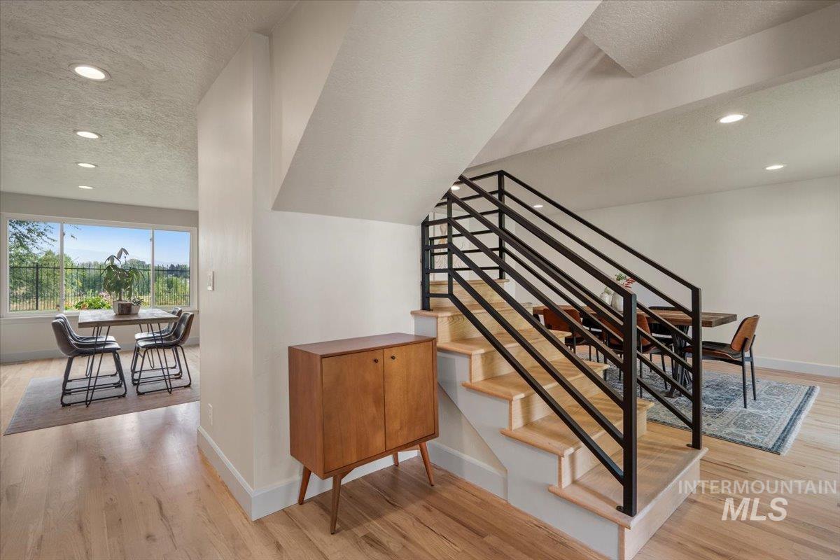Stairs featuring recessed lighting, a textured ceiling, and wood finished floors