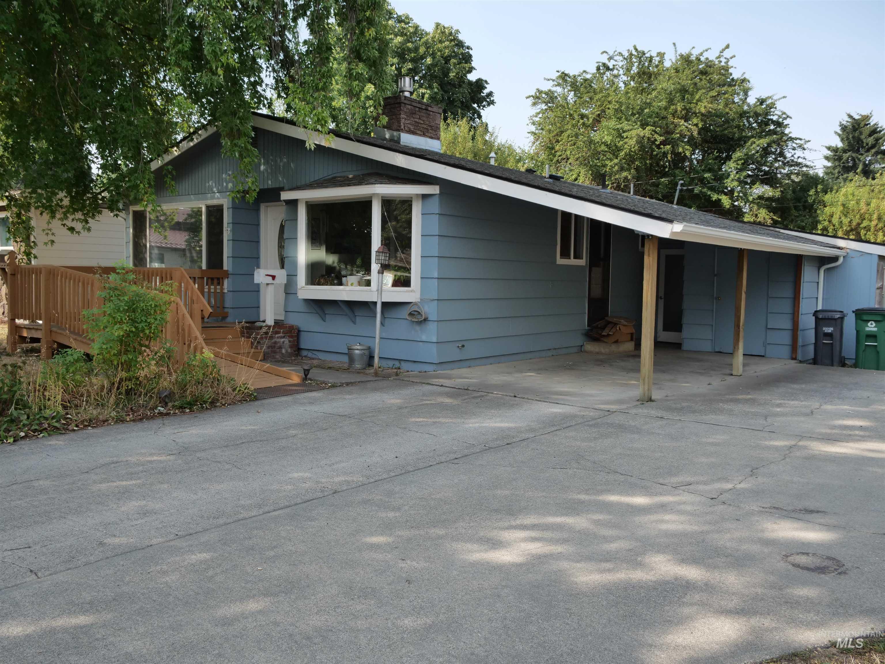View of front of home featuring a carport, driveway, and a chimney