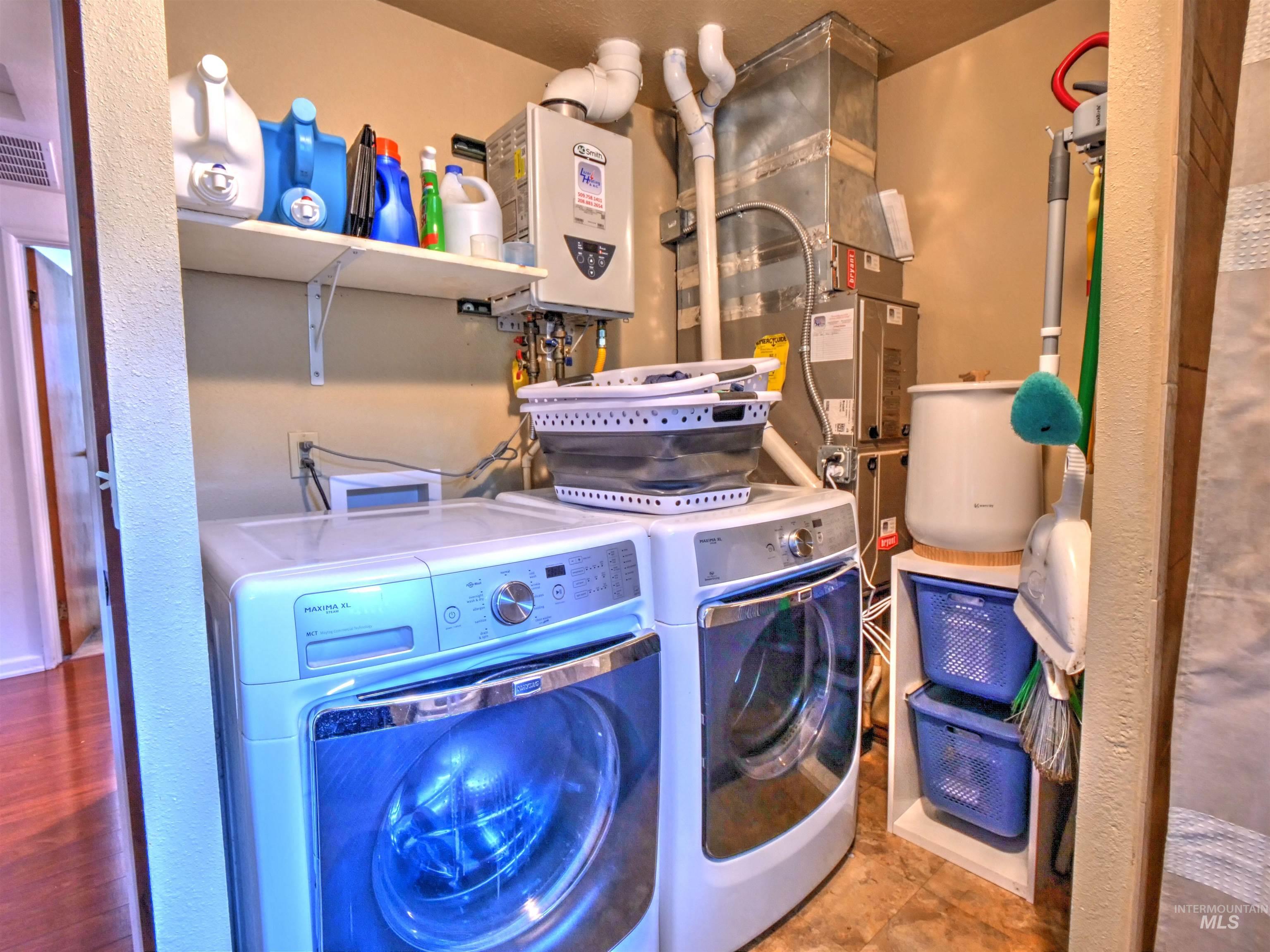 Washroom featuring tankless water heater, washer and clothes dryer, and heating unit