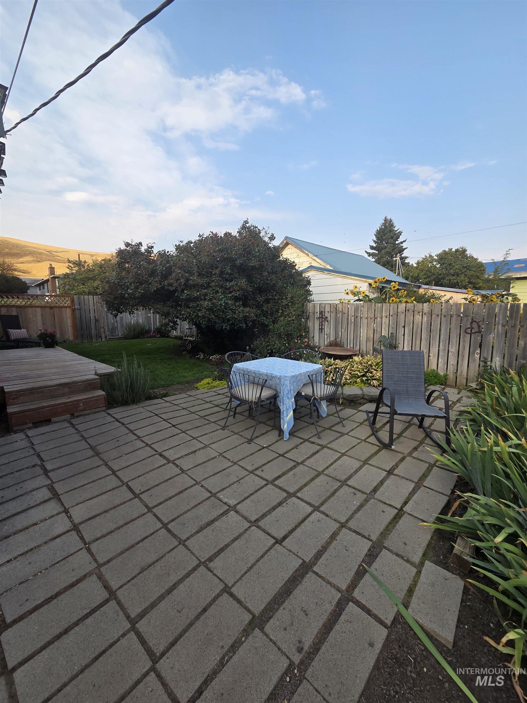 Fenced backyard with a patio, outdoor dining area, and a wooden deck