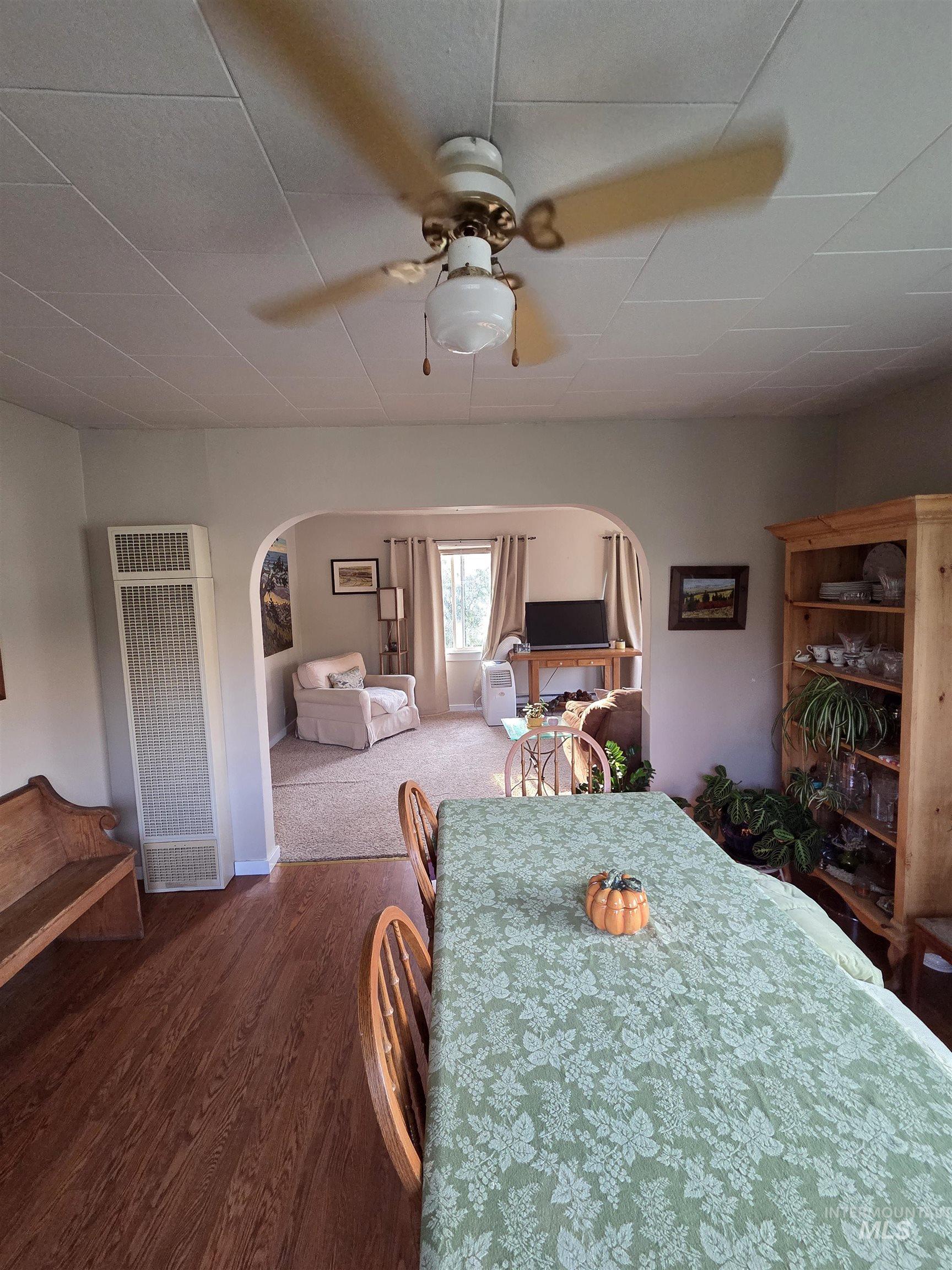 Dining room with a heating unit, dark wood finished floors, and arched walkways