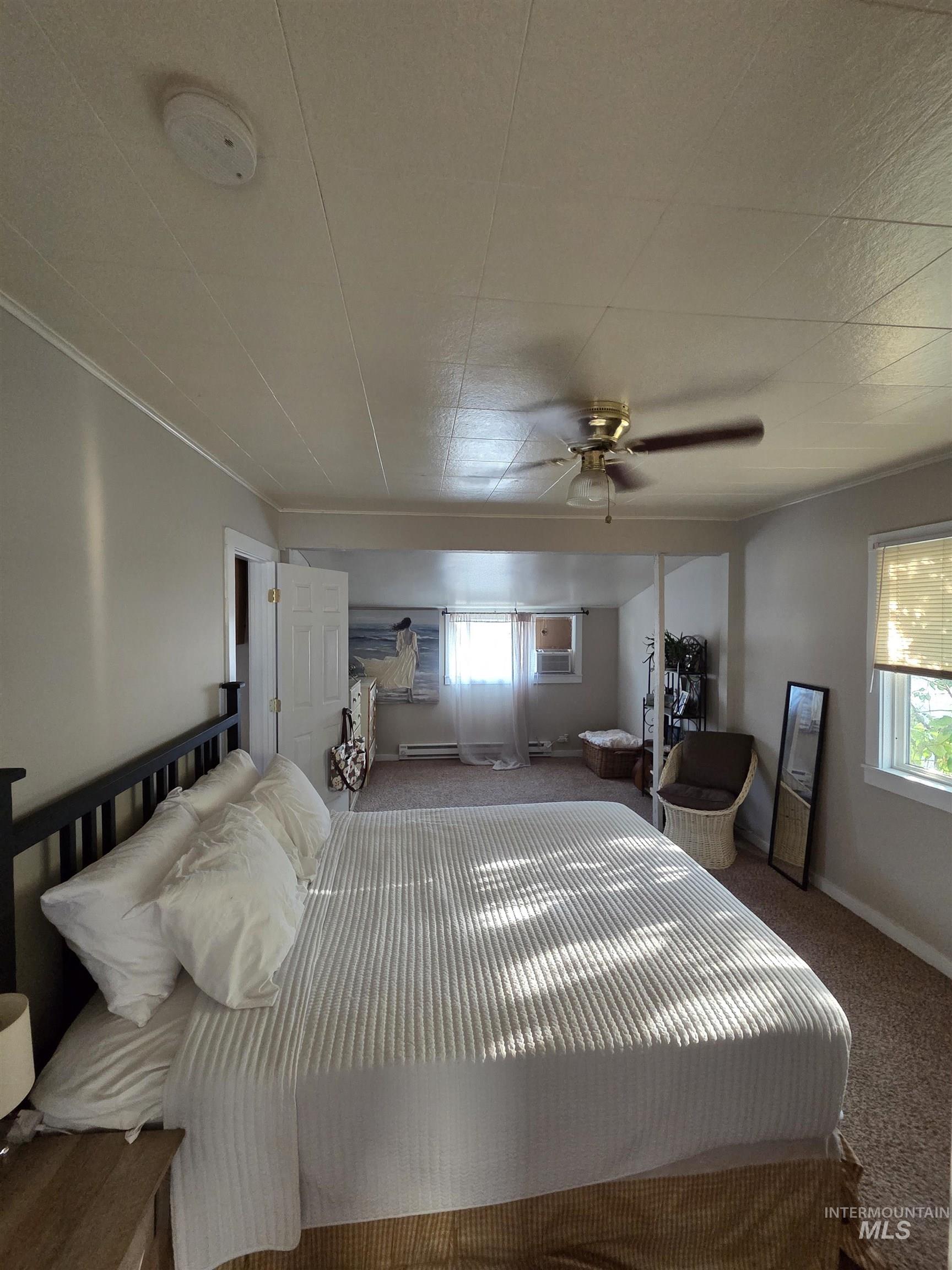 Carpeted bedroom with ceiling fan and a baseboard heating unit