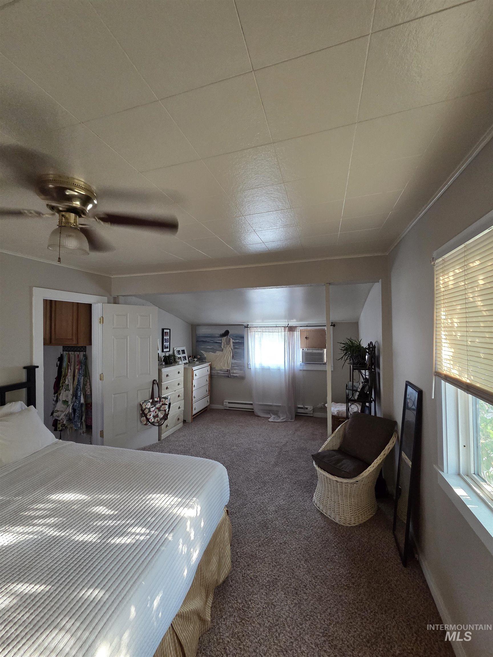 Bedroom with carpet, crown molding, ceiling fan, and baseboard heating