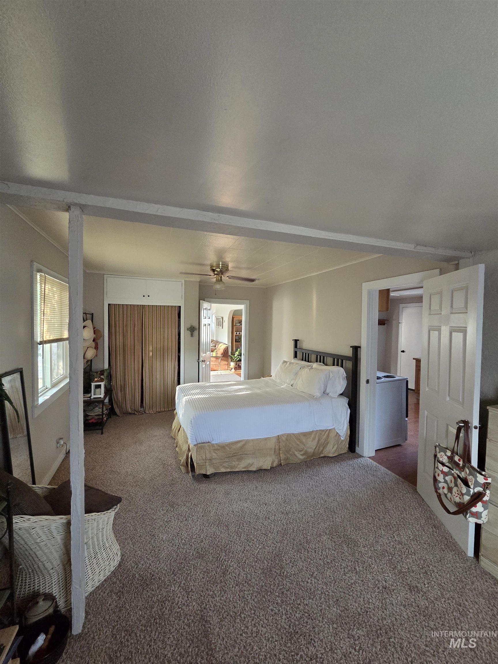 Carpeted bedroom featuring a ceiling fan and beam ceiling