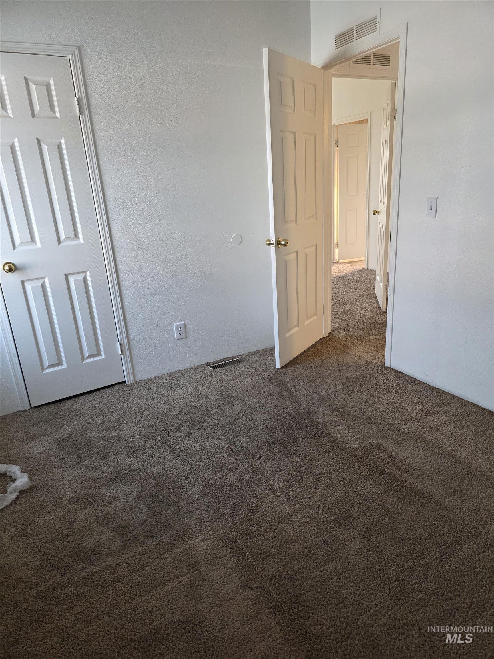 Unfurnished bedroom with dark colored carpet