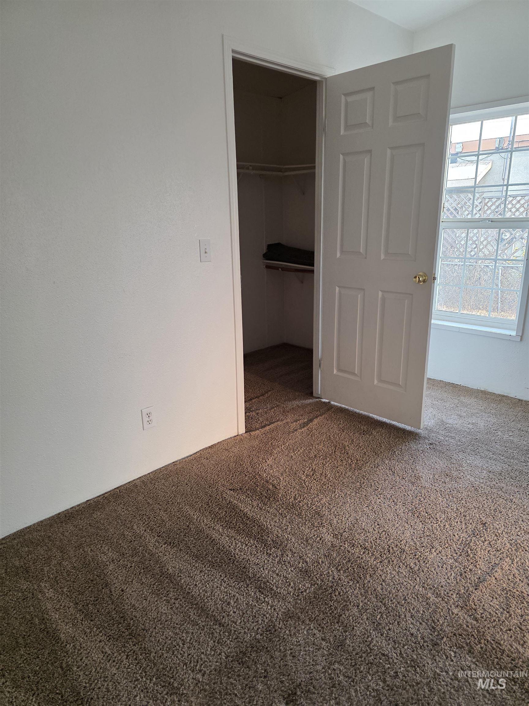 Unfurnished bedroom with carpet and a walk in closet