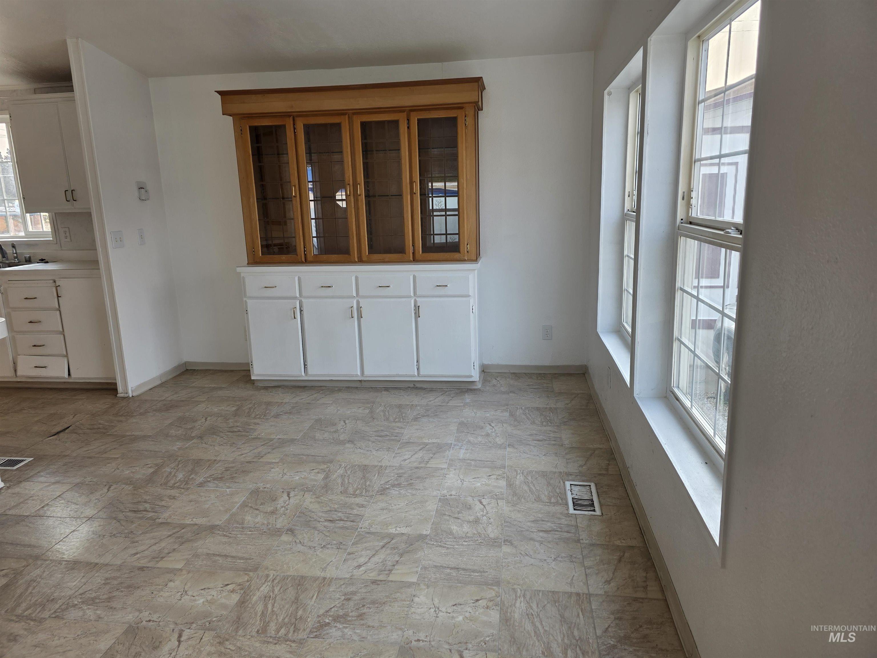 Unfurnished dining area featuring baseboards and light stone finish flooring