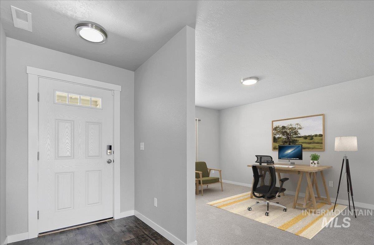 Foyer entrance featuring a textured ceiling and dark carpet