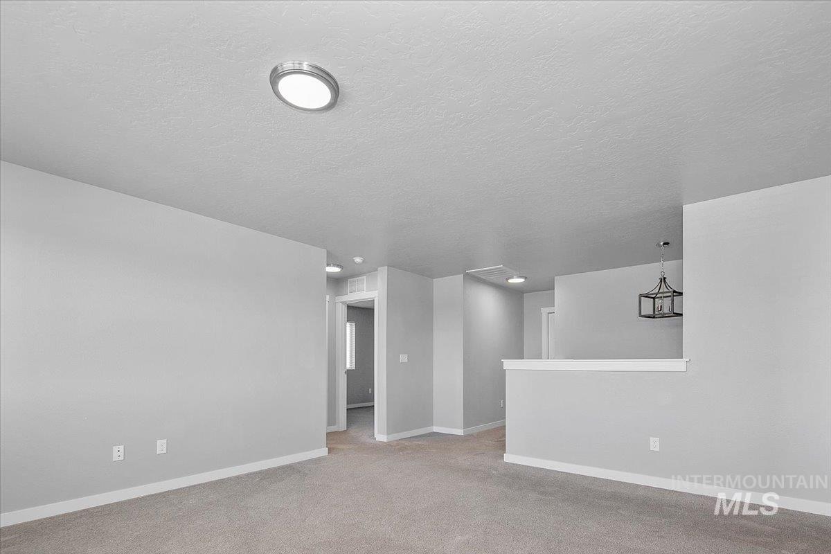 Empty room featuring light carpet and a textured ceiling