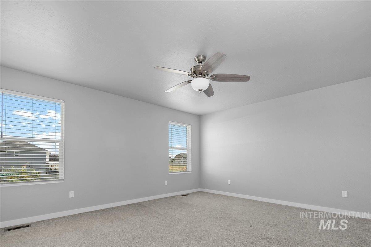 Spare room featuring light colored carpet, ceiling fan, and a textured ceiling