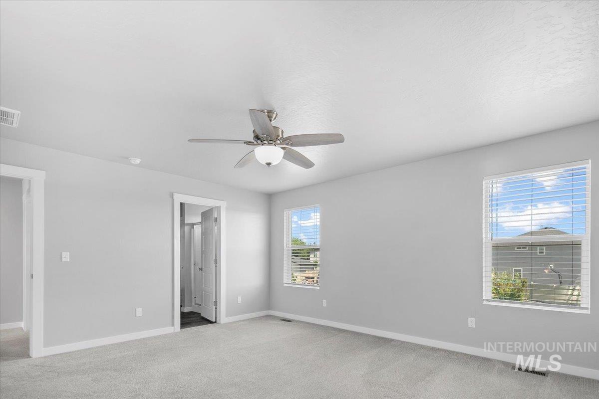 Unfurnished bedroom featuring light colored carpet, a ceiling fan, and connected bathroom