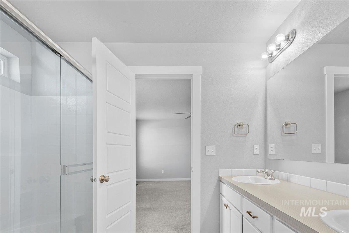 Bathroom featuring a stall shower and double vanity