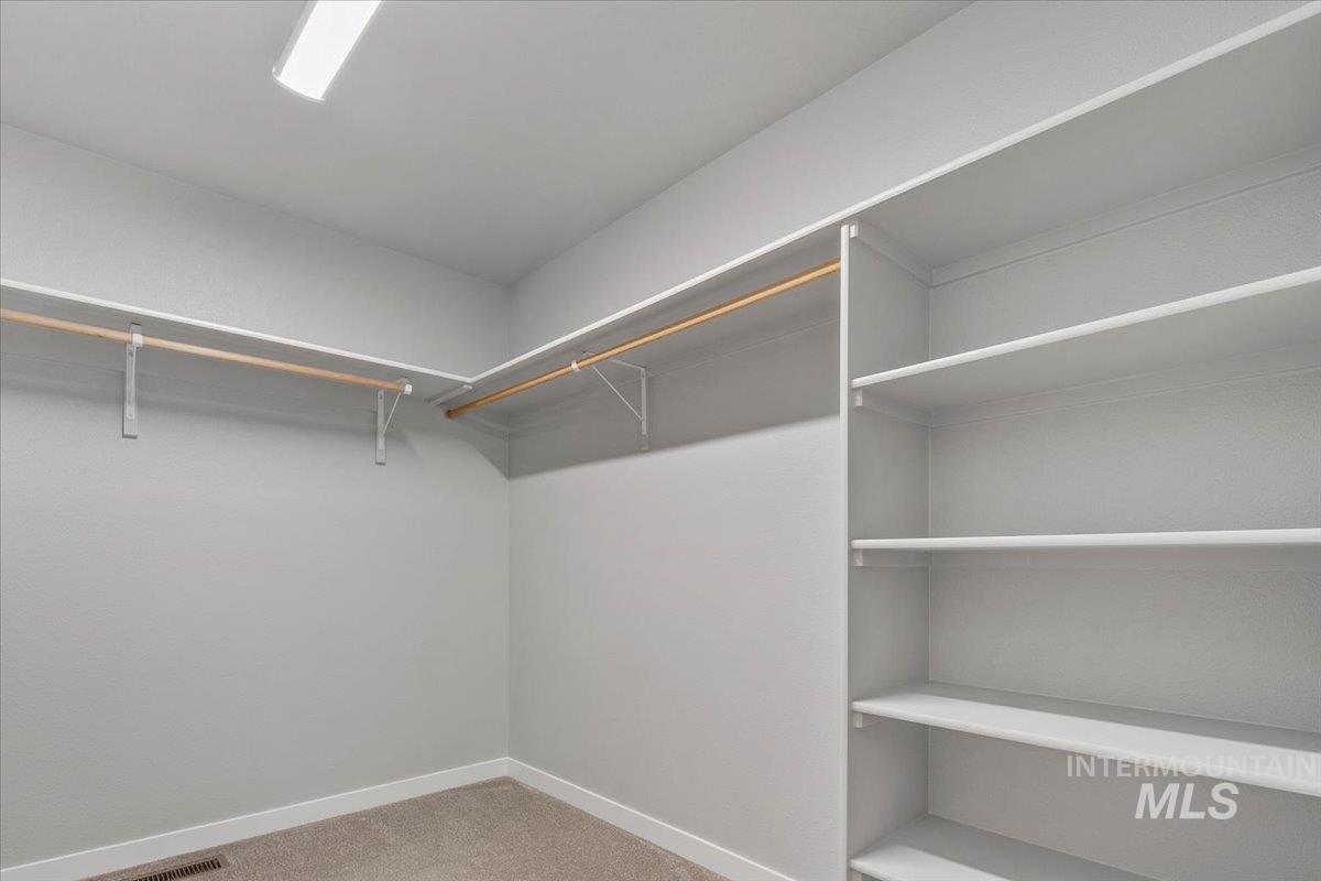 Walk in closet featuring light colored carpet