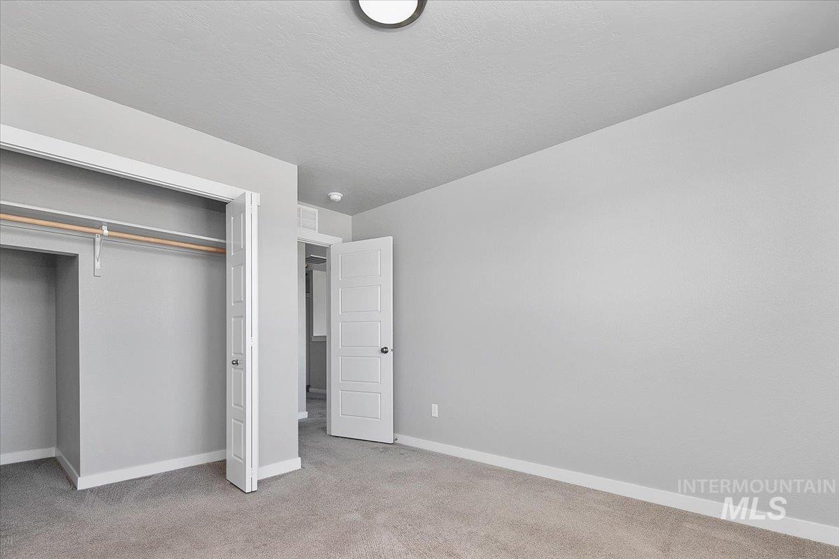 Unfurnished bedroom featuring light colored carpet, a closet, and a textured ceiling