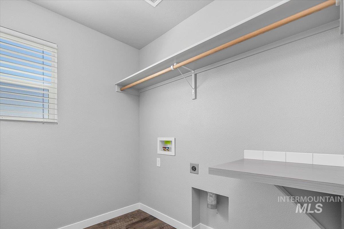 Laundry area with dark wood finished floors, a textured wall, washer hookup, and hookup for an electric dryer