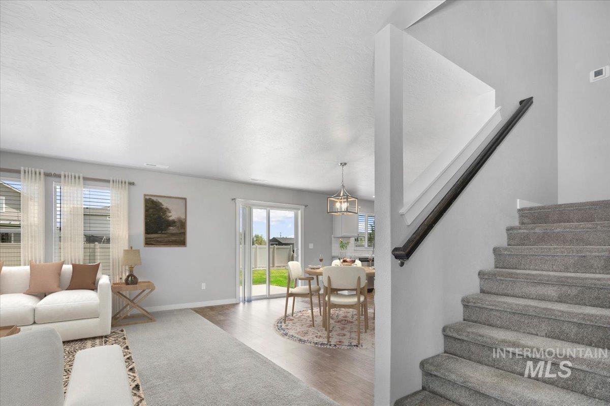 Living room with wood finished floors, a textured ceiling, stairs, and a chandelier