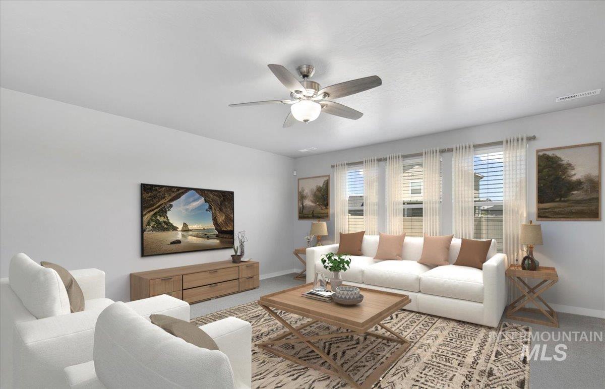 Carpeted living room featuring baseboards and a ceiling fan
