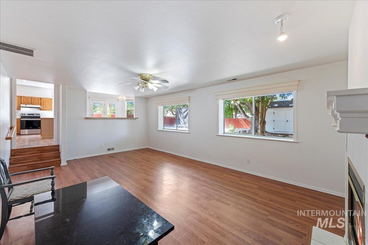 Unfurnished living room with a fireplace with flush hearth, light wood-type flooring, healthy amount of natural light, and a textured ceiling