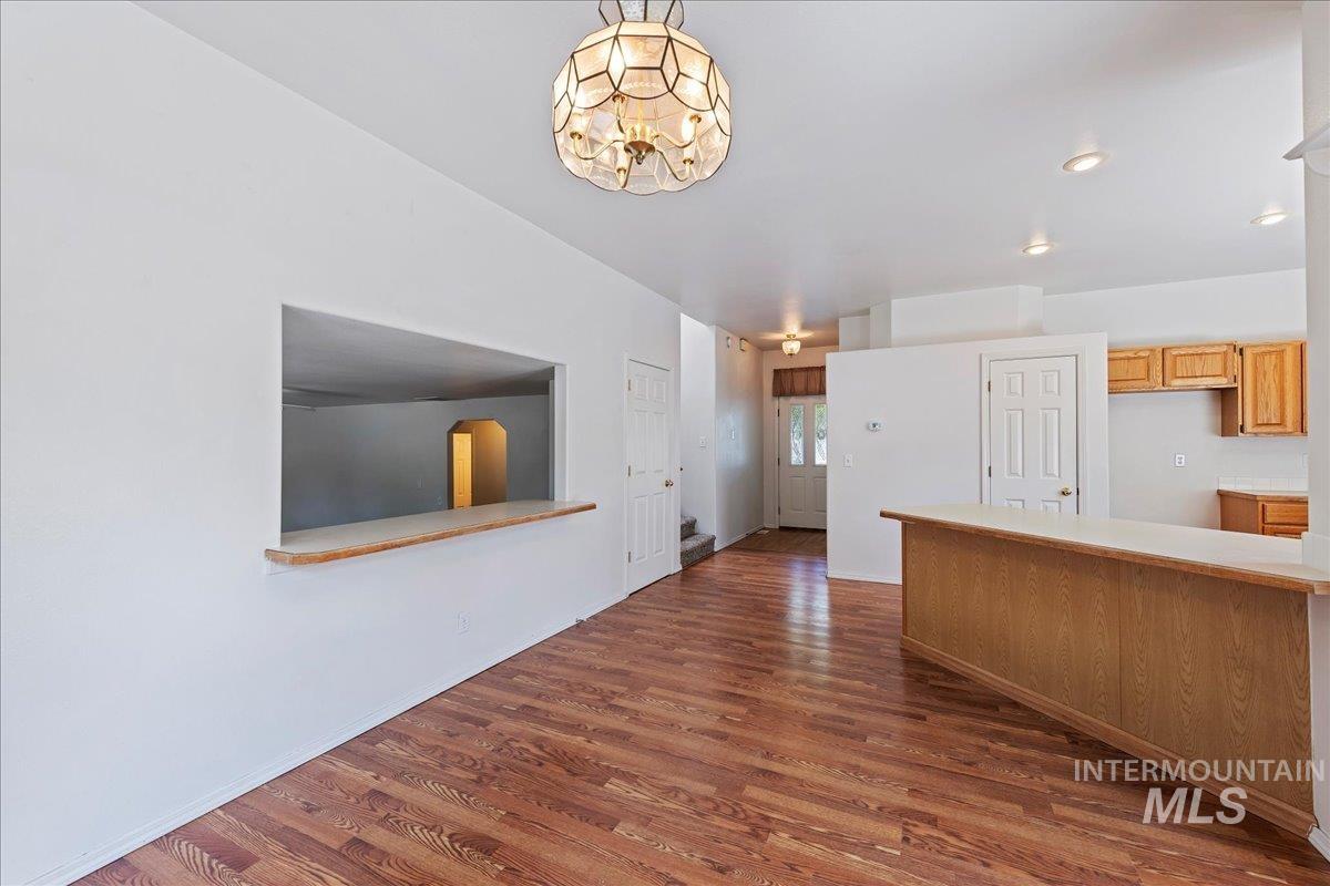 Kitchen featuring light countertops, dark wood-type flooring, recessed lighting, a peninsula, and decorative light fixtures