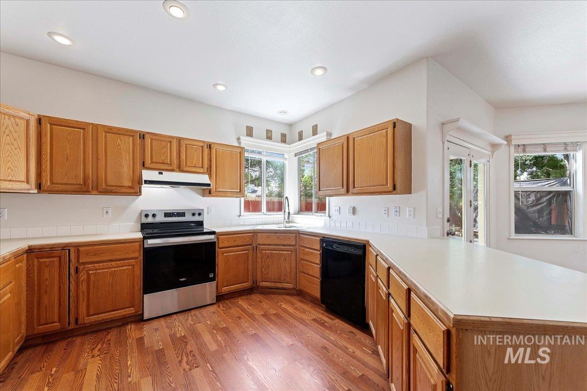 Kitchen with stainless steel electric stove, light countertops, light wood-type flooring, a peninsula, and recessed lighting