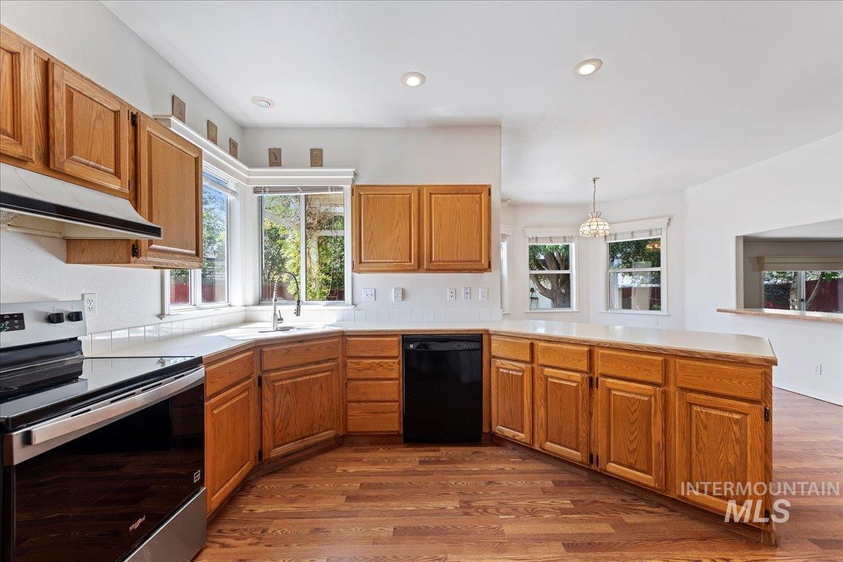 Kitchen featuring electric range, brown cabinets, dishwasher, dark wood-style floors, and recessed lighting