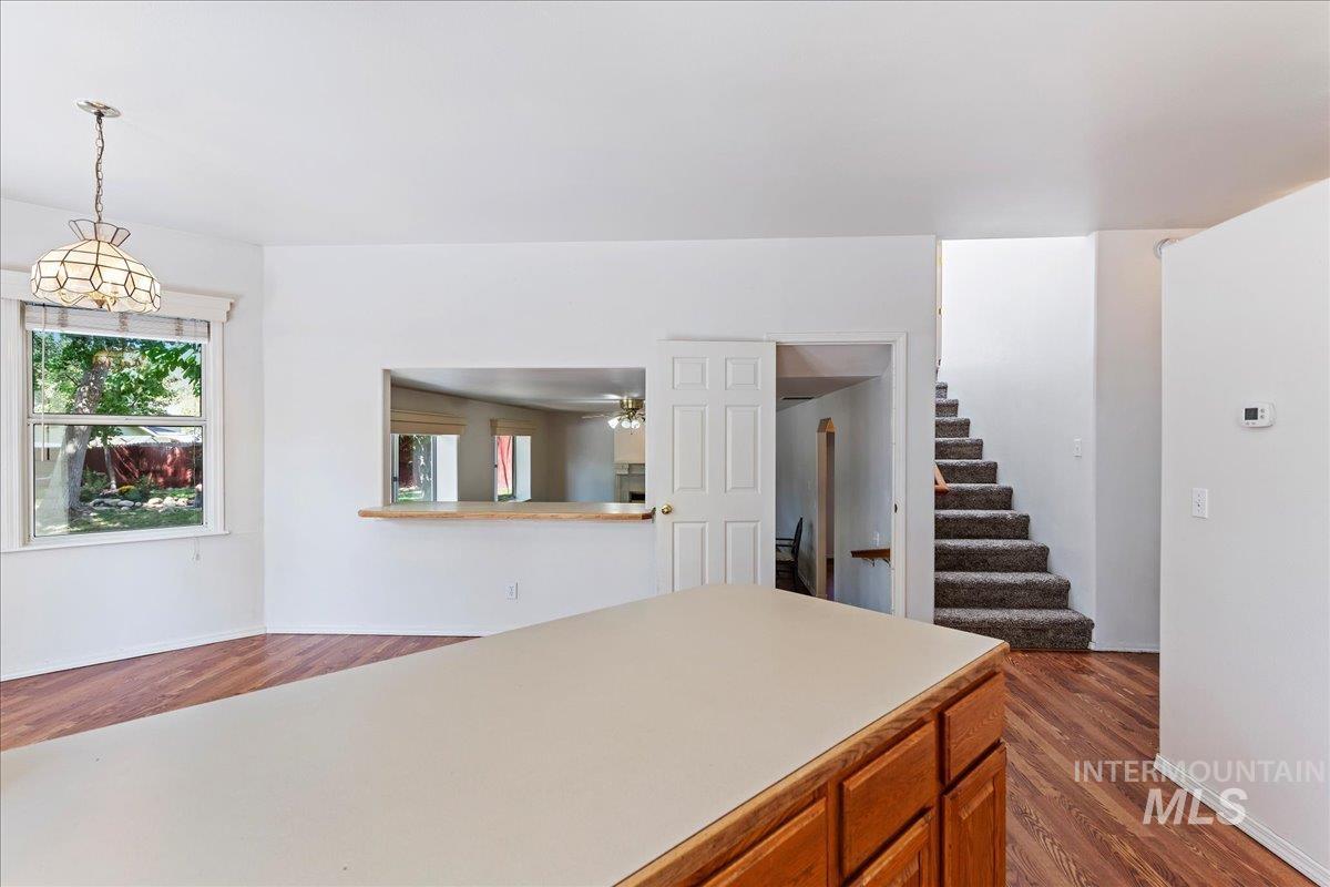 Kitchen featuring light countertops, dark wood-type flooring, brown cabinets, and hanging light fixtures