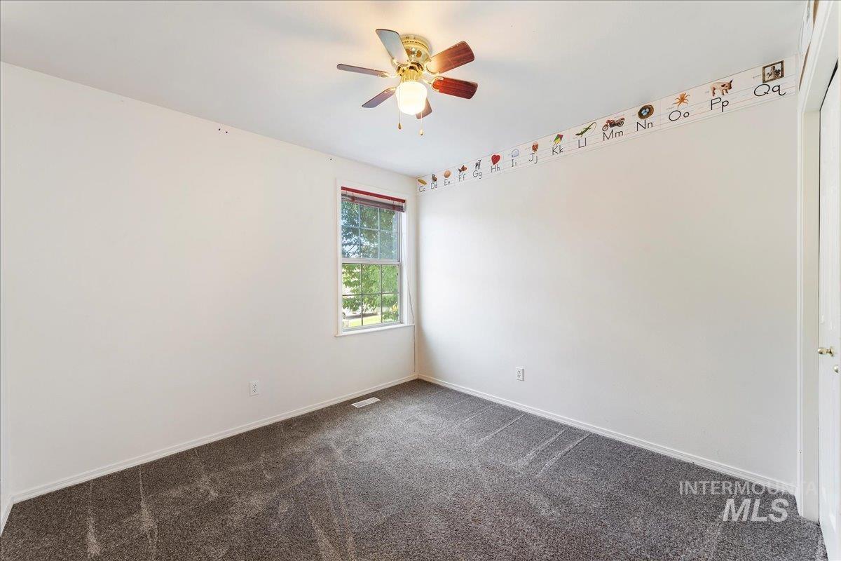 Spare room with dark carpet and ceiling fan