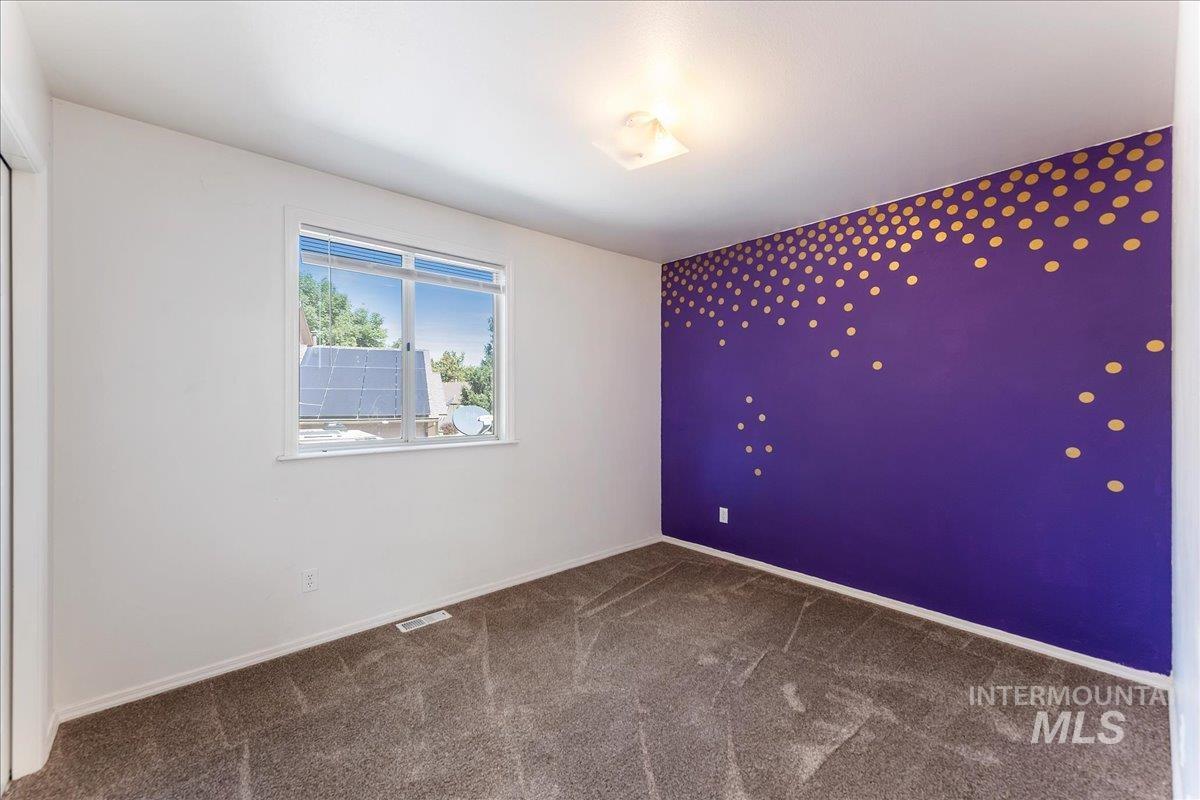 Unfurnished room featuring dark colored carpet and baseboards