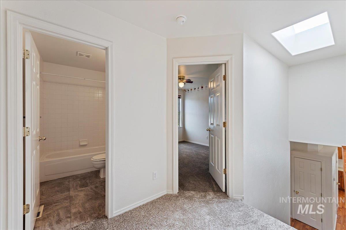 Hall featuring a skylight and light colored carpet