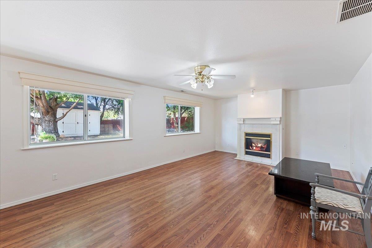 Unfurnished living room with wood finished floors, a fireplace, and a ceiling fan